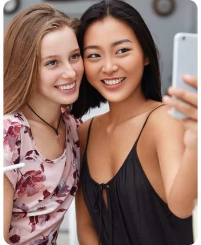 cheerful-two-mixed-race-female-friends-make-photo-front-smart-phone-recreat-together-cafeteria-drink-cocktails-pose-selfie@3x